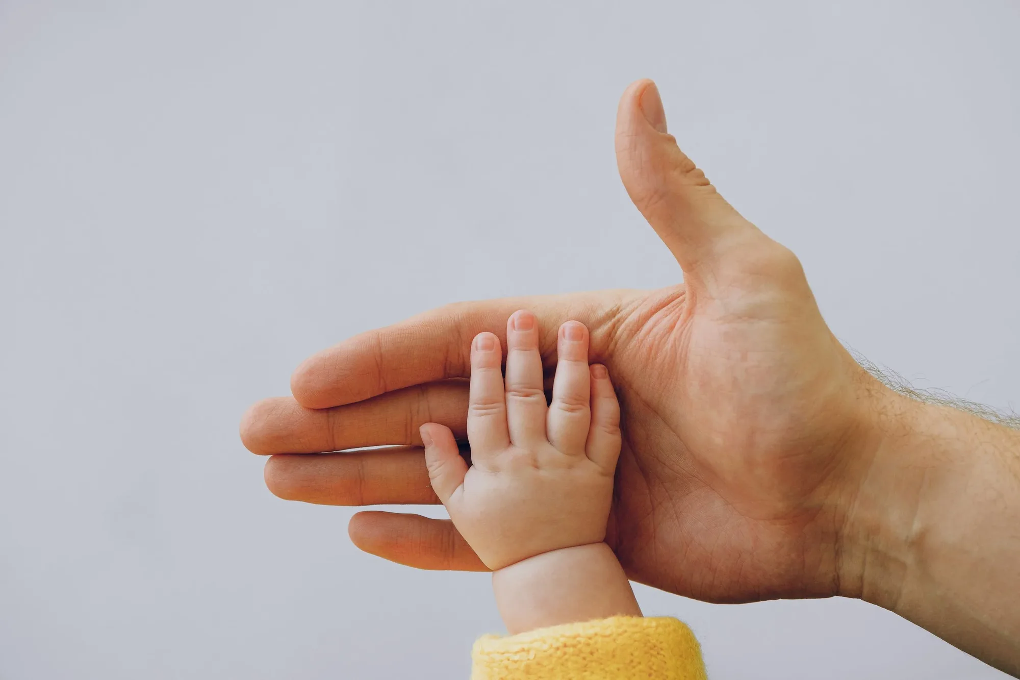 A baby's hand resting in a father's palm
